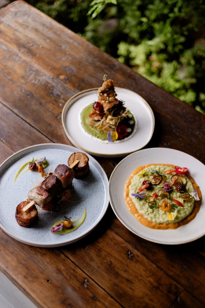Tre portate gourmet: spiedino di carne con patate, tempura di carne e verdure, risotto con verdure e fiori eduli