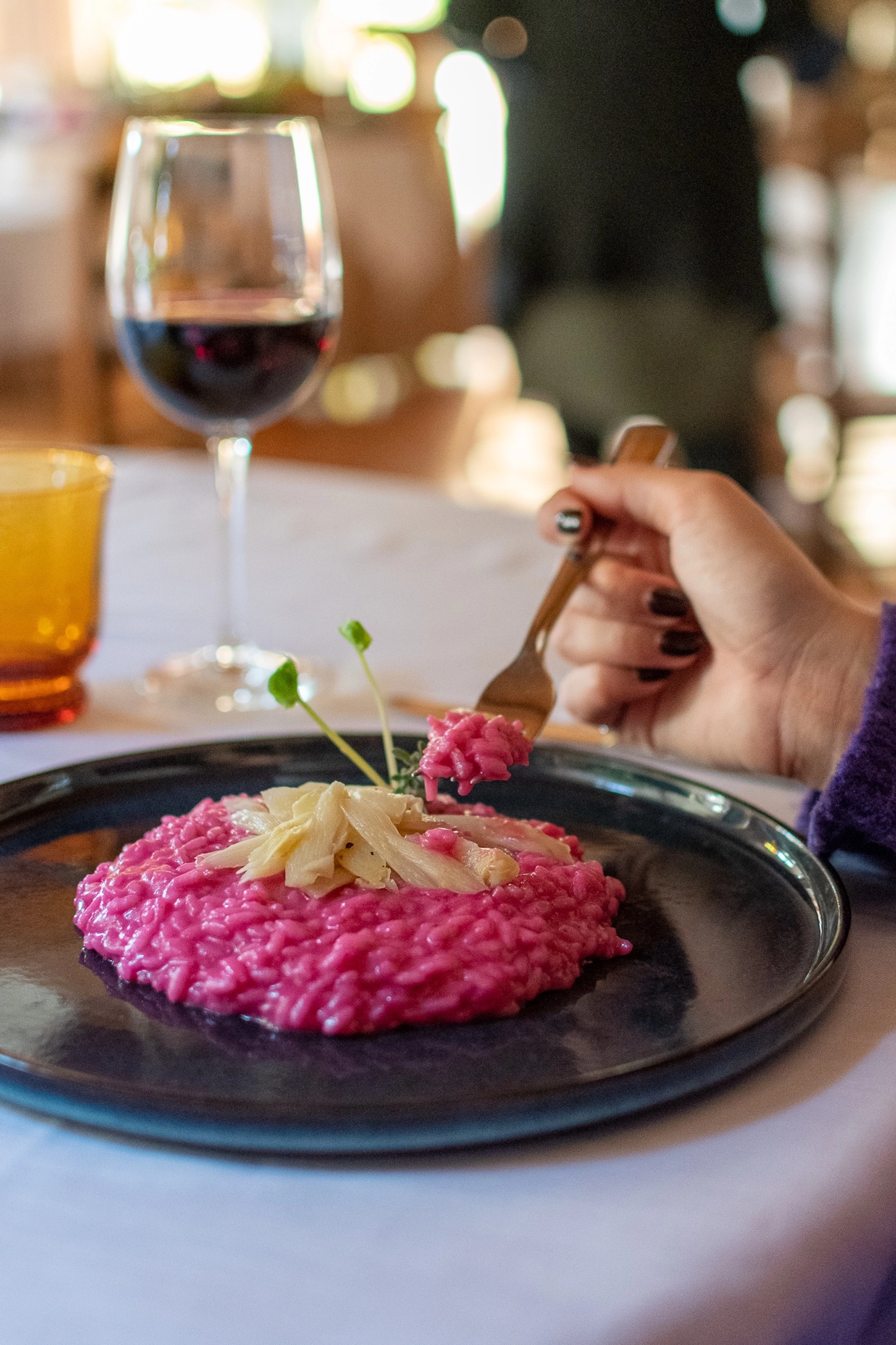 Risotto rosa con decorazione, piatto gourmet servito con calice di vino rosso